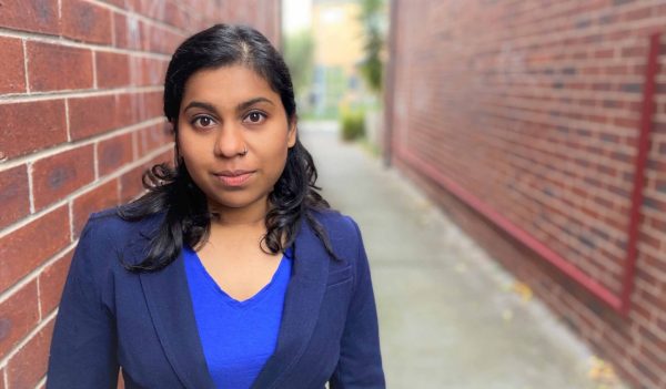 Anya Abseen standing against a brick wall.