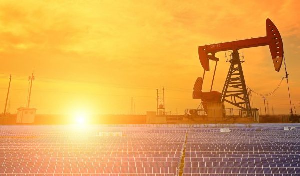 A solar farm with an oil rig in the background