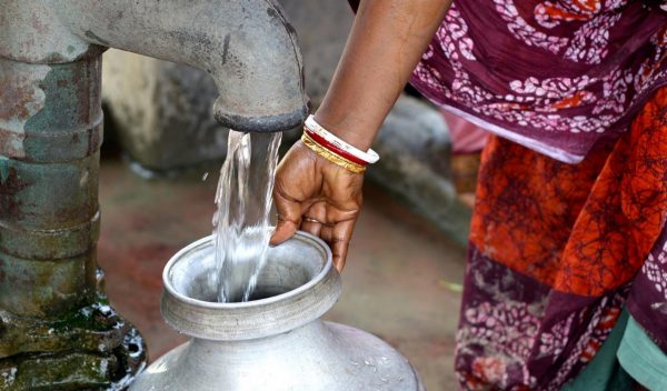 A woman holding a jug at a water spout