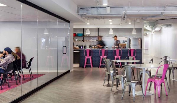 Social Tables workspace including kitchen island and tables next to windowed boardroom.