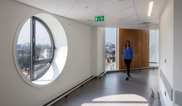 A woman walking along a corridor that has a round window