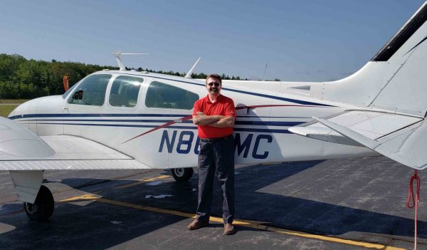 Erv Deck pictured in front of plane at Wiscasset Municipal Airport, Maine