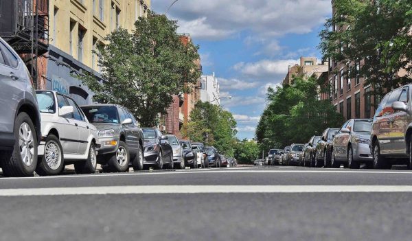 Row of cars parked on either side of an urban street.