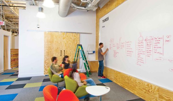 People collaborating in front of whiteboard in a coworking space.