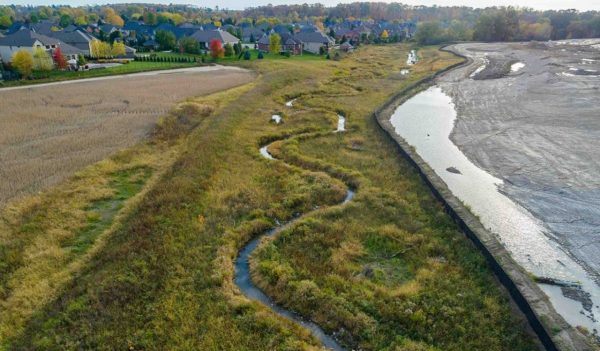 Aerial view of narrow stream running between farmland.