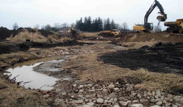 Excavators working next to stream in need of rehabilitation.