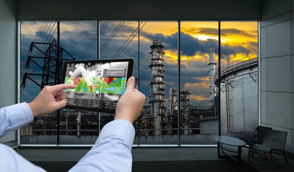 Industry 4.0 concept .Man hand holding tablet with Augmented reality screen and automate wireless Robot arm software at industrial room in smart factory.Window showing oil refinery industry background