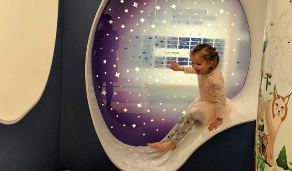 A young girl repurposes a resting space into a slide at the Women’s Auxiliary Volunteers SickKids PlayPark.