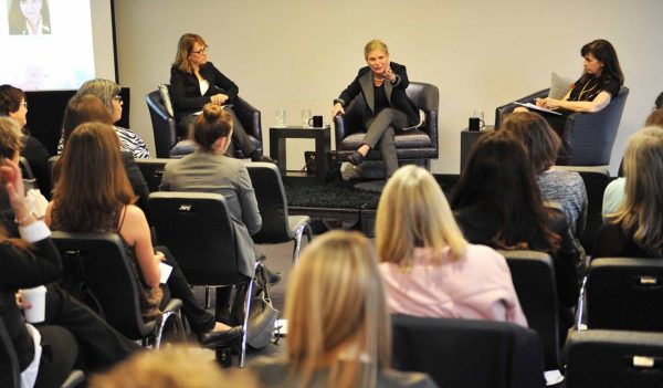 Three panelists speaking to a large group.