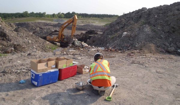 Worker on site moving and testing soil