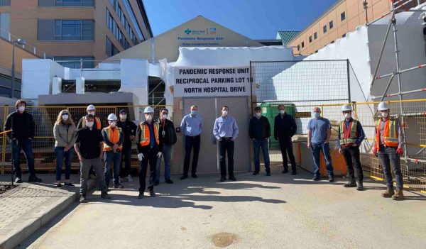 People standing in front of treatment center in safety gear