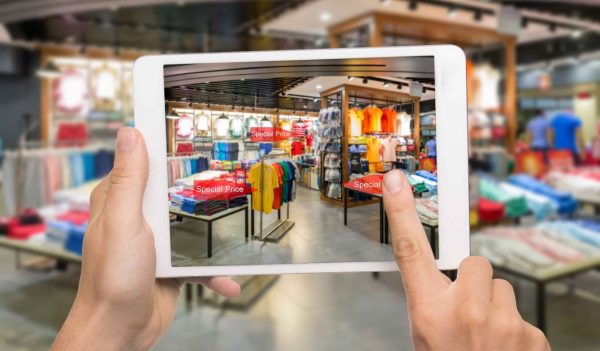 Augmented reality marketing concept. Hand holding digital tablet smart phone use AR application to check special sale price in retail fashion shop mall