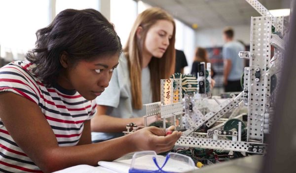 Two Female College Students Building Machine In Science Robotics Or Engineering Class