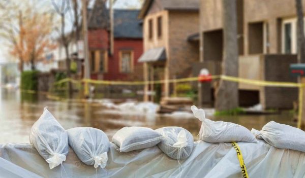 Close shot of flood Protection Sandbags with flooded homes in the background