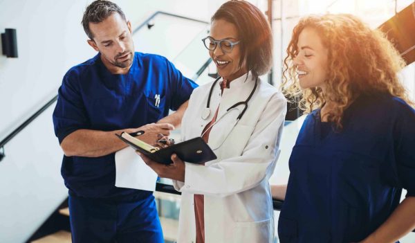 Diverse group of medical professionals standing together in a hospital corridor discussing a patient's dignosis