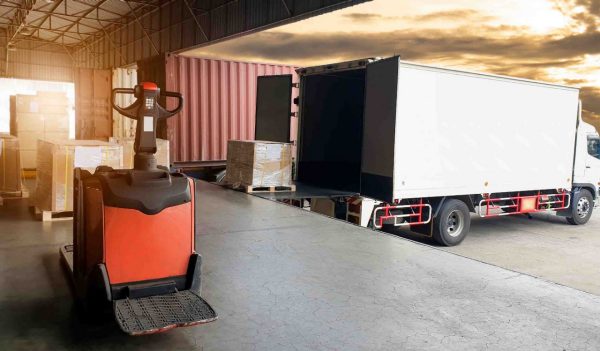 Packaging Boxes on Pallet Loading into Shipping Cargo Container. Trucks Parked Loading at Dock Warehouse. Distribution Center. 