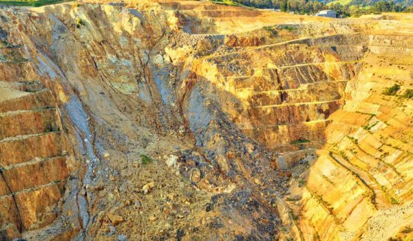 Open-cast gold mine, with terraces for transporting ore along the edges of the pit. One wall of the mine has collapsed in a rockslide. Martha Mine, Waihi, New Zealand