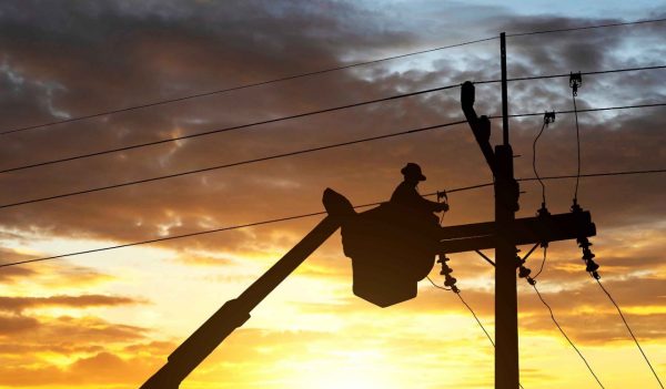 electrician works on cable car to maintain high voltage transmission lines.