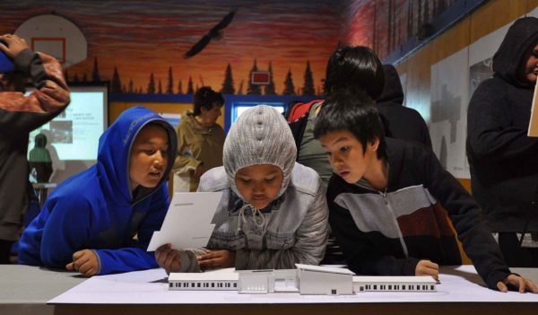 Students at a community open house looking at a building model of a new school.