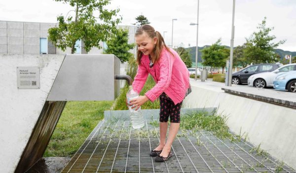 Girl filling a water bottle at an outdoor filling station.