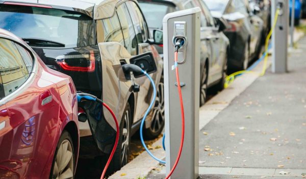 Row of electric vehicles using EV charging stations along a curb.