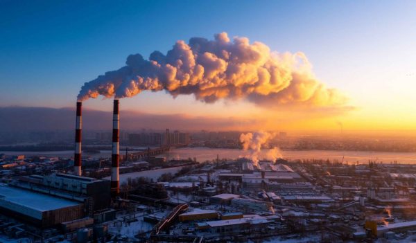 Industrial manufacturing plant with emissions coming out of the smoke stacks at dusk.