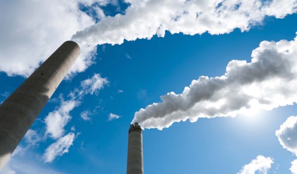 Close up of industrial smoke stacks against the blue sky.