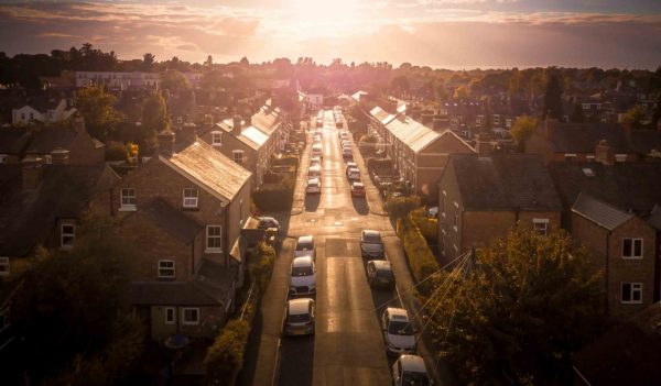 Sun rising above a traditional British housing estate with countryside in the background.