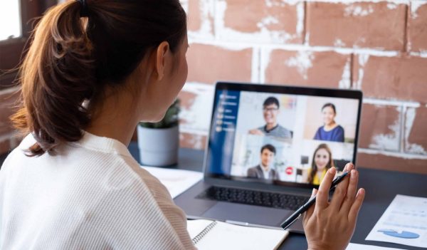 Female having a virtual meeting with her team on a laptop.