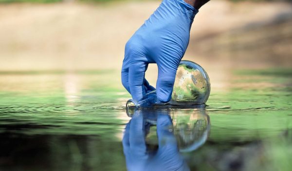 Water sample. Hand in glove collects water to explore. Concept - water purity analysis, environment, ecology. Water testing for infections, permission to swim