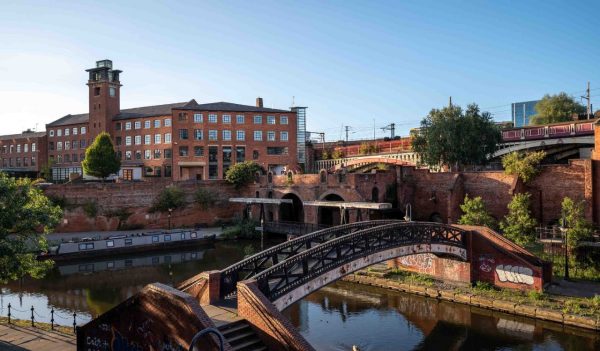 Narrowboat moored on Bridgewater Canal in Deansgate against a blue skyline from Castle field Basin, Manchester, north-west England