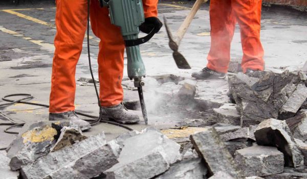 Workers at construction site demolishing asphalt