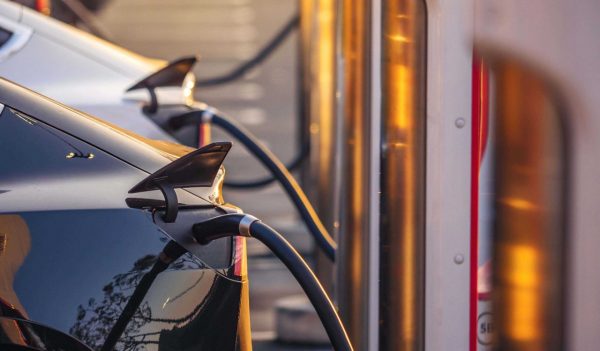 Electric cars charging at charging station outdoors at sunset.