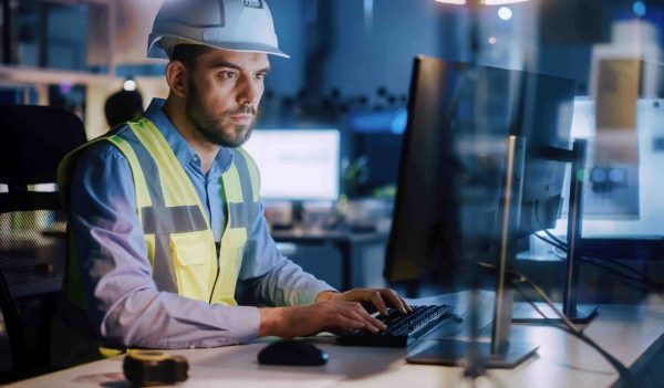 Male factory operations worker on a computer,.