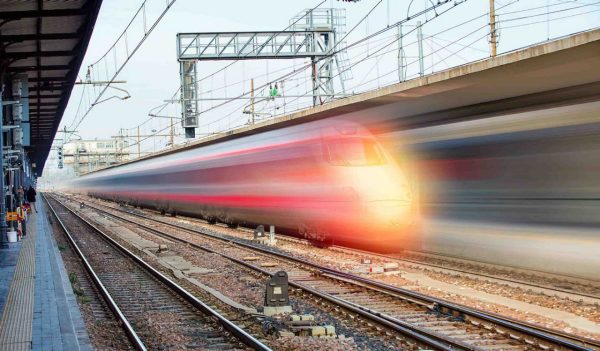 Blue high speed train runs on rail tracks 