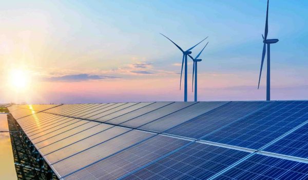 Wind turbines and solar panels at sunset.