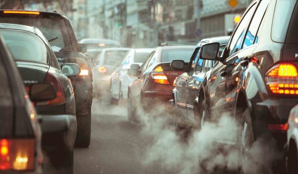 Traffic jam on a city street with heavy exhaust clouds.