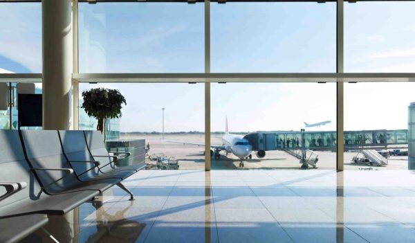 Interior seats in an airport terminal overlooking the tarmack with a plane.