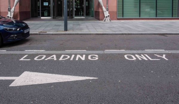 Loading zone only parking in front of a building with signage painted on roadway.