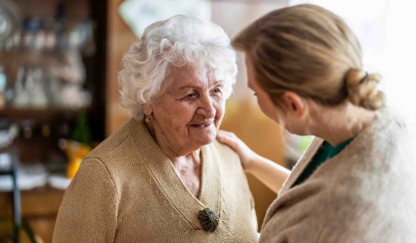 An elederly woman talking with another woman.