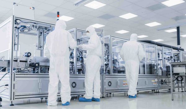 In the Manufacturing Facility Team of Scientist Wearing Sterile Protective Coverall Set's up / Programs Modern Industrial 3D Printer, High Precision Manufacture of Semiconductors under Process.