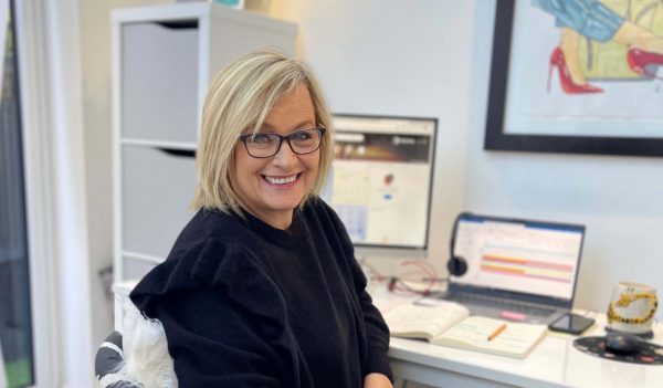 Leisa Ward sitting at her desk with a computer monitor in the background.