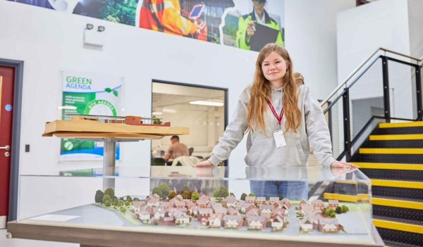 Erin Baker standing in front of a display case showing a model of a residential neighbourhood.