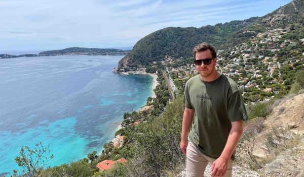 Fred Hartley walking on a hill, overlooking the ocean and a neighbourhood.