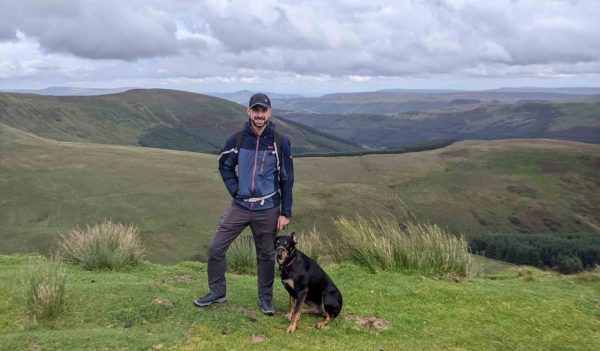 Lewis standing on a bluff with his dog.