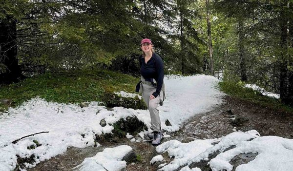 Roberta Rogers hiking on a path in spring that has snow in the ground.