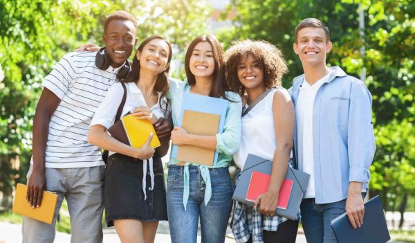 College Friendship Concept. Happy Multiethnic Group Of Students Posing Outdoors, Embracing And Smiling At Camera, Free Space