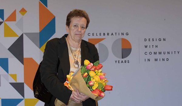 Milena Cominetta in front of the anniversary banner.