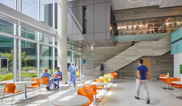 Interior seating in a common area with large windows and staircase in background.