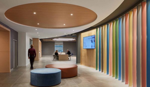 Office common area with colorful feature wall and people meeting.